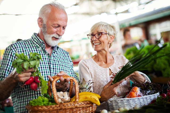 A couple shopping for vegetables at a farmer’s market.