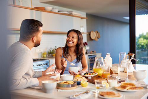 Couple smiling while enjoying meal together at home.