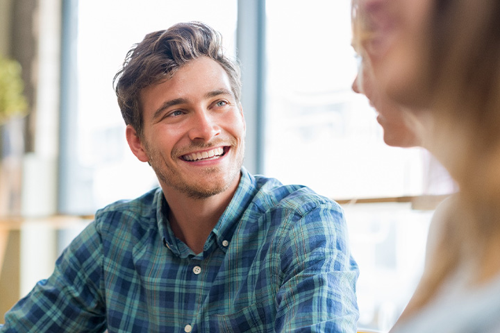 Man in blue shirt smiling at friend.