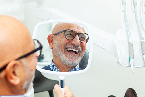 Man with black glasses smiling in mirror.