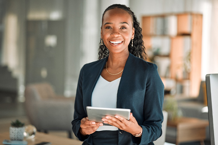 Woman smiling while holding tablet in office.