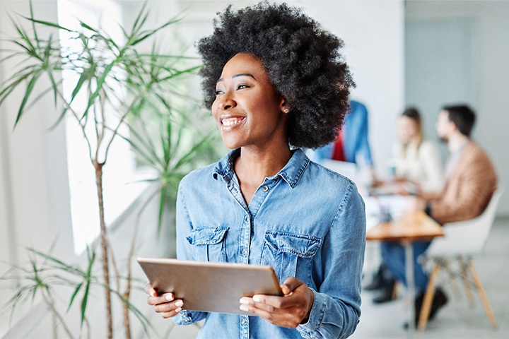 Woman smiling while holding tablet in office.