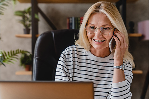 Woman with glasses smiling while talking on phone.