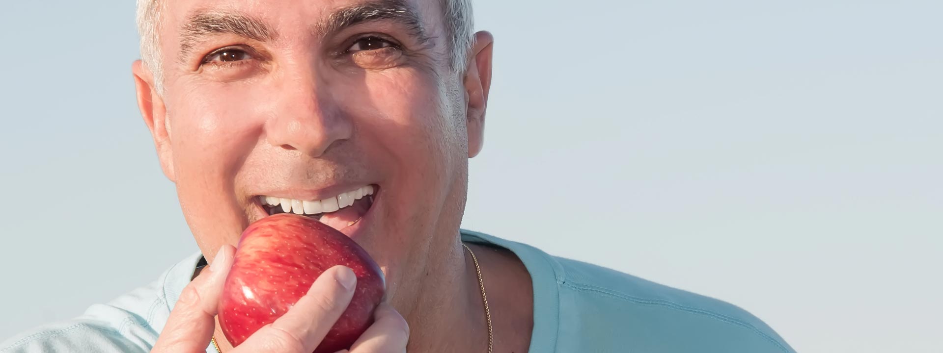 A man happily eating an apple after having root canal treatment